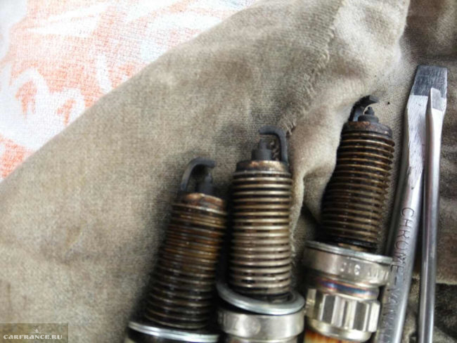 Старые свечи с нагаром из двигателя автомобиля Пежо 308 и две отвертки